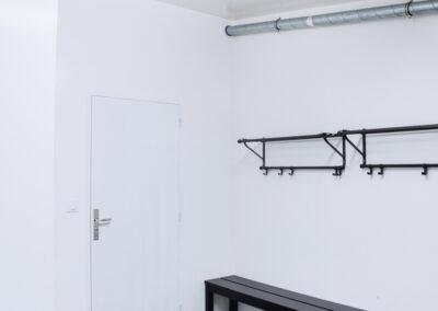 Vue d'un vestiaire simple et moderne avec un sol sombre en dalles.