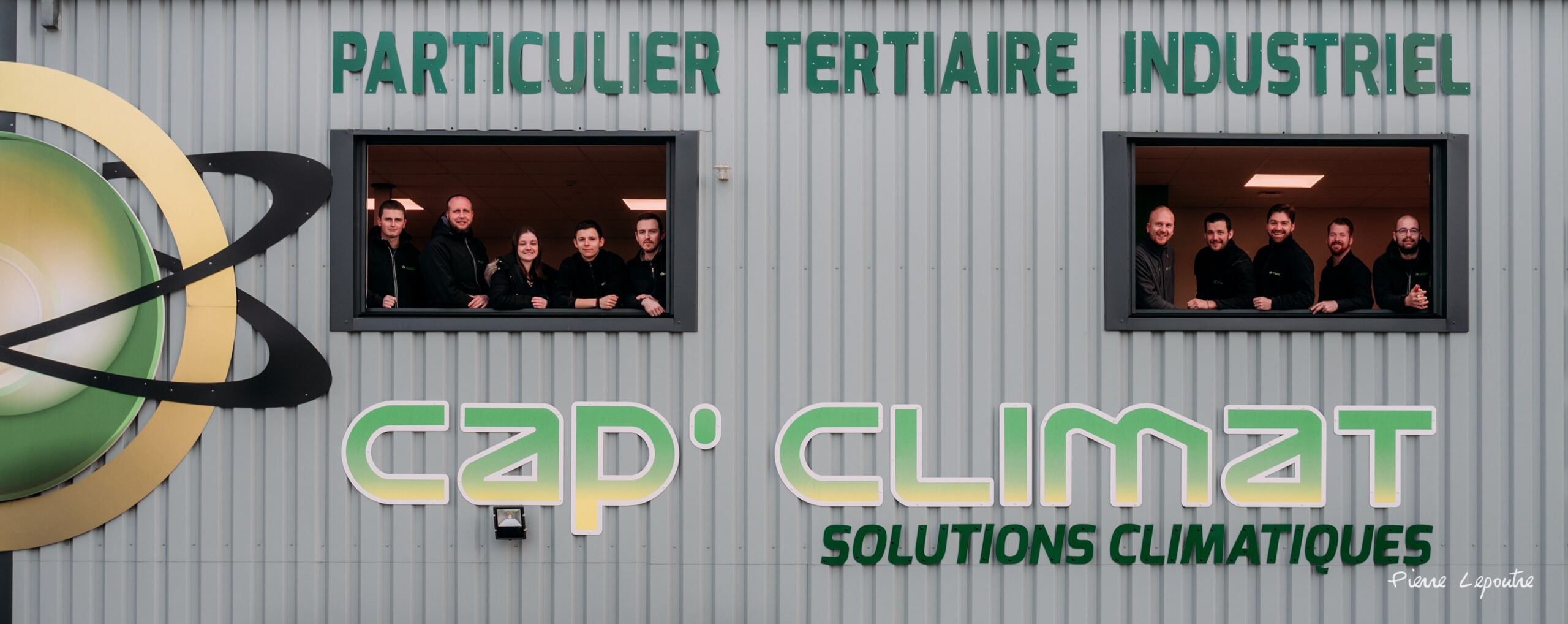 Équipe de Cap’Climat posant aux fenêtres du bâtiment de l’entreprise, spécialisé en solutions climatiques pour particuliers, tertiaire et industriel.