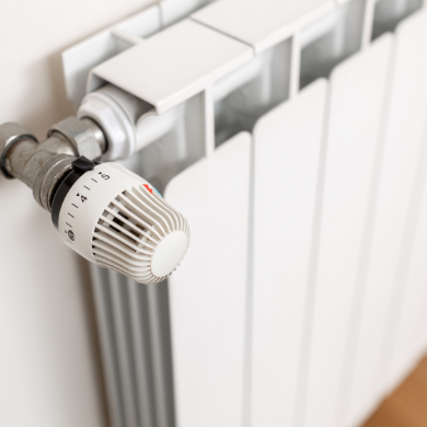 Gros plan sur un radiateur blanc moderne équipé d'une vanne thermostatique réglée sur le chiffre 4.